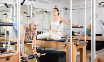 Canvas Print - Smiling elderly woman in sportswear training pilates performer bed in gym