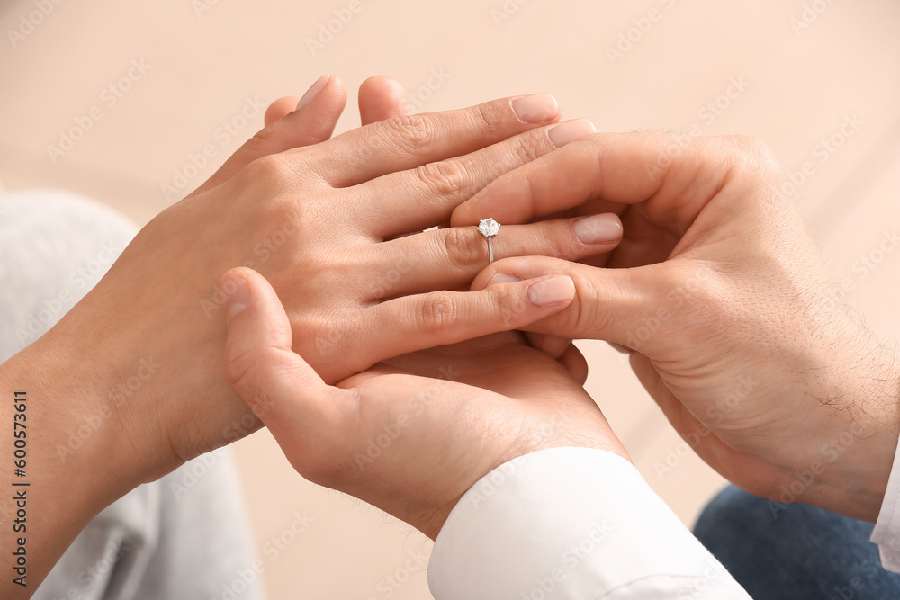 Man putting engagement ring on woman's finger, closeup