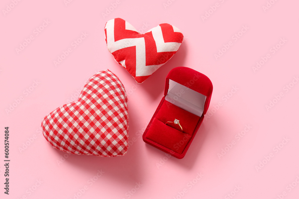 Box with engagement ring and hearts on pink background