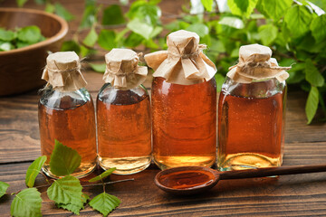 Wall Mural - Bottles of birch essential oil, infusion or tincture. Birch syrup or coal tar oil bottles. Twigs of Birch tree with leaves. Alternative herbal medicine.