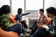 © sofiko14 - Focus on caucasian female in glasses pointing at sketches while holding staff briefing in workplace with terracotta beanbags. International architects being engaged in efficient housing project.