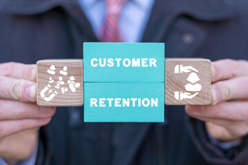 Man holding colorful blocks with icons and inscription: CUSTOMER RETENTION. Concept of customer acquisition and retention business marketing. Incentive and welfare program. Retain clients.