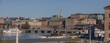 View over the bay Strömmen, old town Gamla Stan, Government buildings museums and the Opera house, pier with moored commuting boats, a sunny early tranquil summer day in Stockholm
