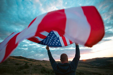 Wall Mural - Man holding a waving american USA flag.