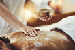 Woman, hands and relax in salt scrub for skincare, exfoliation or relaxation at indoor beauty spa. Hand of masseuse rubbing salts on female back for physical therapy, massage or treatment at resort