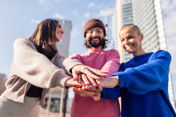 three smiling friends holding hands in unity, focus on hands, concept of friendship and bonding