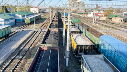 Railway tracks, containers filled with coal and gravel. Transportation of goods by means of railway transportation tanks. Top view on railways with various cargo wagons. Import and export logistics.