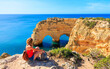 © M.studio - Woman tourist enjoying beautiful cave or heart shape rock formation in atlantic ocean- Algarve coast in Portugal
