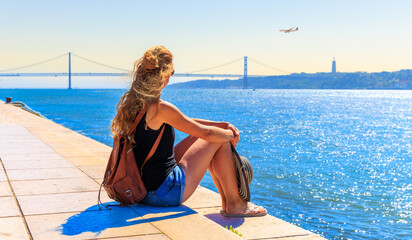 Wall Mural - Woman looking at plane in the sky in Lisbon- Travel destination, tour tourism,travel desire concept