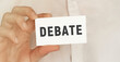 © MP Studio - Card with text Debate in a man's hand