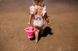 © Cavan Images - Child on sandy beach walking away with pink bucket on summer vac