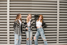 Three Happy Teen Girls Posing In Front Of Strong Vertical Lines.