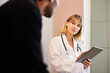 © Cavan Images - Blond female doctor holding tablet PC while looking at male patient