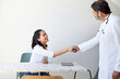 © Cavan Images - Mature male doctor doing handshake with female patient in clinic