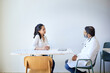 © Cavan Images - Female patient discussing with male doctor sitting on chair in clinic