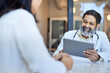 © Cavan Images - Happy male doctor using tablet PC sitting with female patient