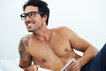 Book, Happy Shirtless Young Man With Glasses And On A Bed In White Background. Nerd Or Smart, Male Model With Sexy Body And Smiling Person Topless In His Home Or Apartment With Notebook For Reading