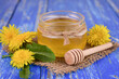 Fresh honey from spring dandelions in a jar on a blue background.Close-up.
