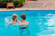 © andrey - Dad and daughter have fun and swim with inflatable circle in the pool.