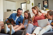 © D Laflor/peopleimages.com - Technology, streaming and a happy family on the sofa for internet, social media and communication. Smile, bonding and a mother, father and children with a tablet and phone for online games at home