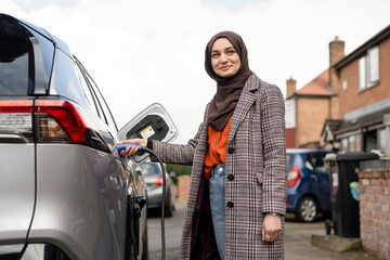 Woman wearing hijab charging electric car