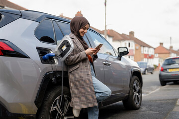 Woman wearing hijab charging electric car