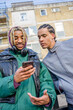 © Cultura Creative - Young male friends using phone outdoors