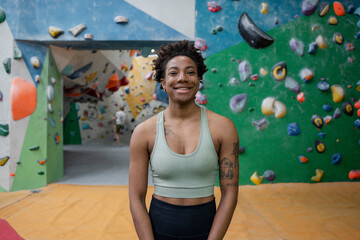 Canvas Print - Portrait of smiling woman standing in front of climbing wall