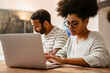 © Drobot Dean - African woman working on laptop while her husband sitting next to her at table