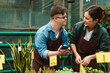 © Drobot Dean - Man with down syndrome and woman florist smiling while working together in greenhouse