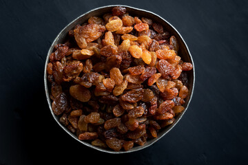 Wall Mural - Dried grapes, raisins in a bowl on dark wooden background. Top view.