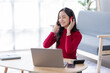 © David - Beautiful Young asian woman at home sitting on the sofa while using laptop phone and headphone listening to music at home