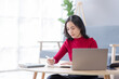 © David - Beautiful Young asian woman at home sitting on the sofa while using laptop and headphone at home