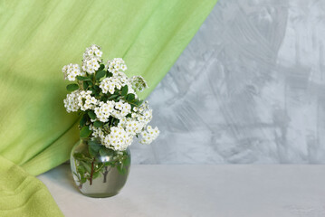 Sticker - Fresh summer bouquet of white flowers in vase on a gray shelf against a gray loft wall. Decor with a green textile curtain. Floral home decor.	