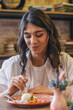 © Tatyana - Portrait of a happy young attractive dark-haired woman eating in a cafe.