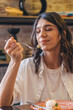 © Tatyana - Portrait of a happy young attractive dark-haired woman eating in a cafe.