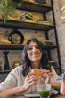 © Tatyana - Portrait of a young attractive dark-haired woman eating a sandwich in a cafe.