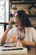 © Tatyana - Portrait of a young attractive dark-haired woman eating a sandwich in a cafe.