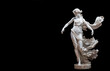 Stunning white marble statue of a graceful woman in motion, standing tall against a stark black background. Marble statue of a ballerina.