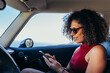© ADDICTIVE STOCK - Ethnic woman using smartphone in car