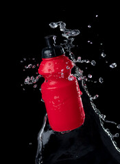 Wall Mural - Red sport bottle with water splash on black background