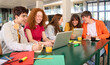 © CarlosBarquero - Smiling college classmates using laptops in campus cafeteria. Group of cheerful caucasian students working and researching together on a university school project.