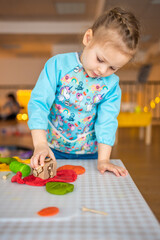 A little girl playing with plasticine. Sensory development and experiences, themed activities with children, fine motor skills development