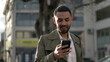 © Marco - One happy Arab young man closeup face smiling while holding cellphone device standing in street. Closeup face of a male Middle Eastern person smiling and using technology
