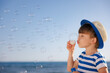 © Sunny studio - Kid having fun on the beach. Boy blowing soap bubbles