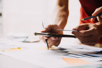 Close up ux developer and ui designer brainstorming about mobile app interface wireframe design on table with customer breif and color code at modern office.Creative digital development agency