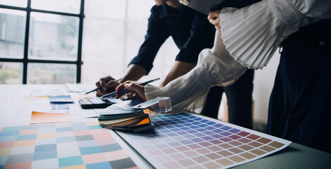 Close up ux developer and ui designer brainstorming about mobile app interface wireframe design on table with customer breif and color code at modern office.Creative digital development agency