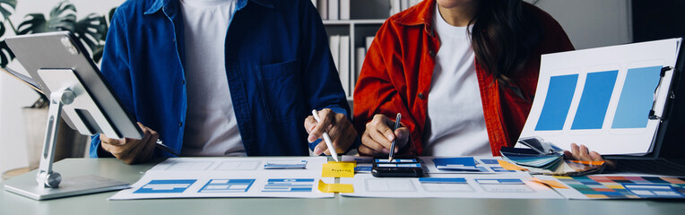 Close up ux developer and ui designer brainstorming about mobile app interface wireframe design on table with customer breif and color code at modern office.Creative digital development agency