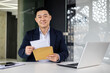 © Liubomir - Portrait of successful businessman inside modern office building, asian man received good news news in envelope opens letter happy smiling and looking at camera.
