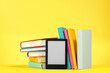 Leinwandbild Motiv Modern e-book reader and hard cover books on yellow background